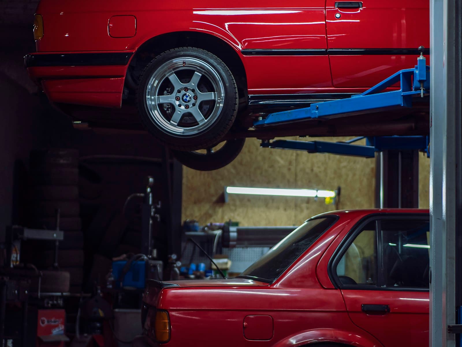 A car on a workshop lift above a second car